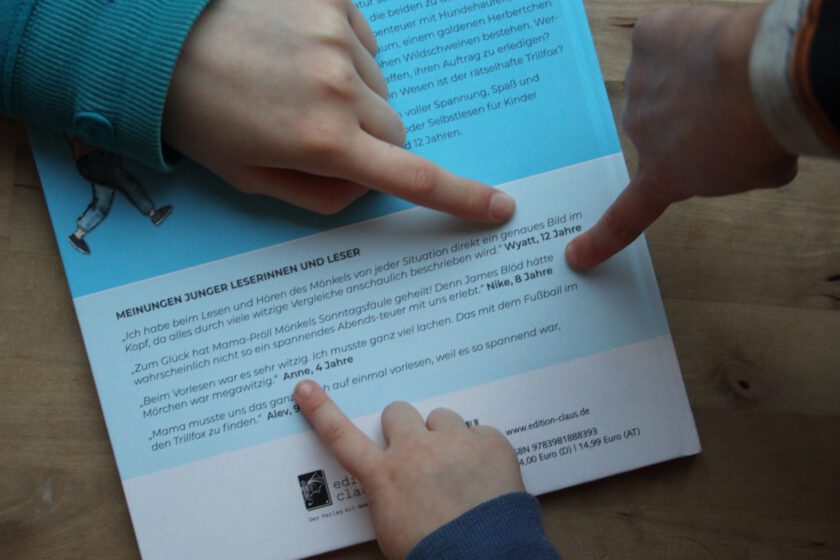 Trillfox im Moor - Mönkel Band 2 Drei Kinderfinger zeigen auf den Buchrücken von "Der Mönkel und der Trillfox im Moor". Dort stehen Zitate von ihnen über das Buch.