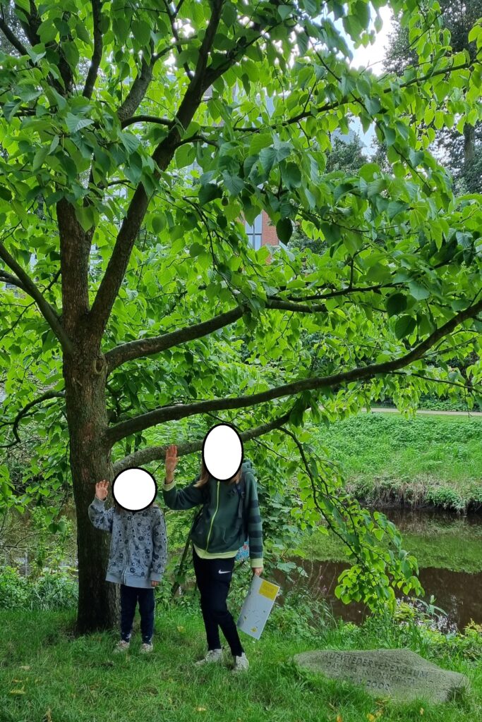 Die Kinder stehen unter einem Baum und Winken.