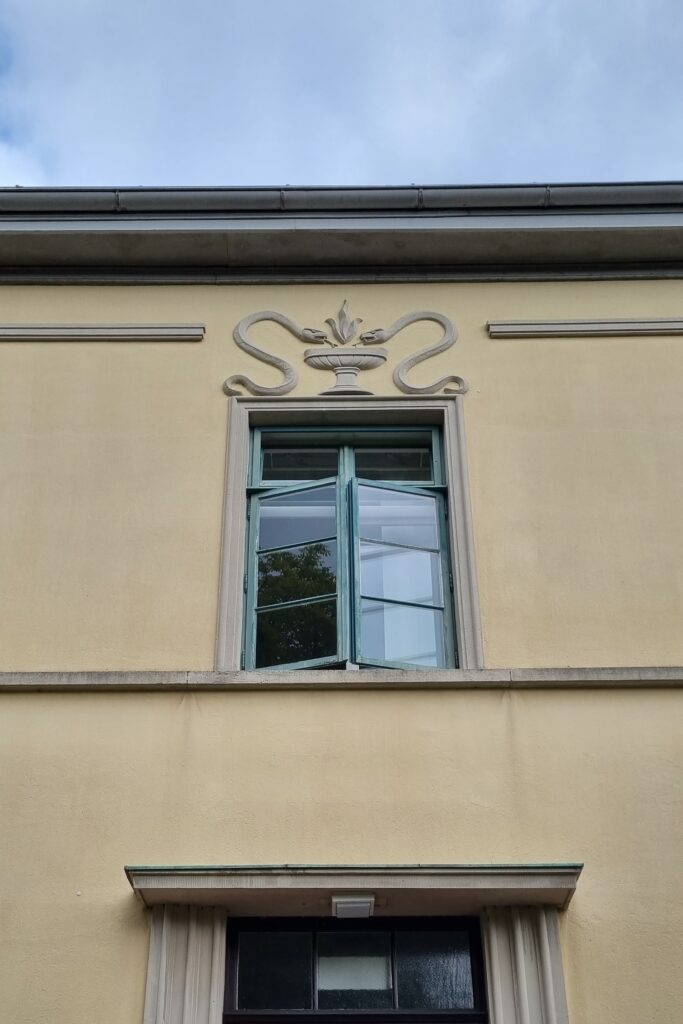 Oben an der Fassade eines Gebäudes sind Schlangen zu sehen, was uns ohne die Kulturelli nie aufgefallen wäre.